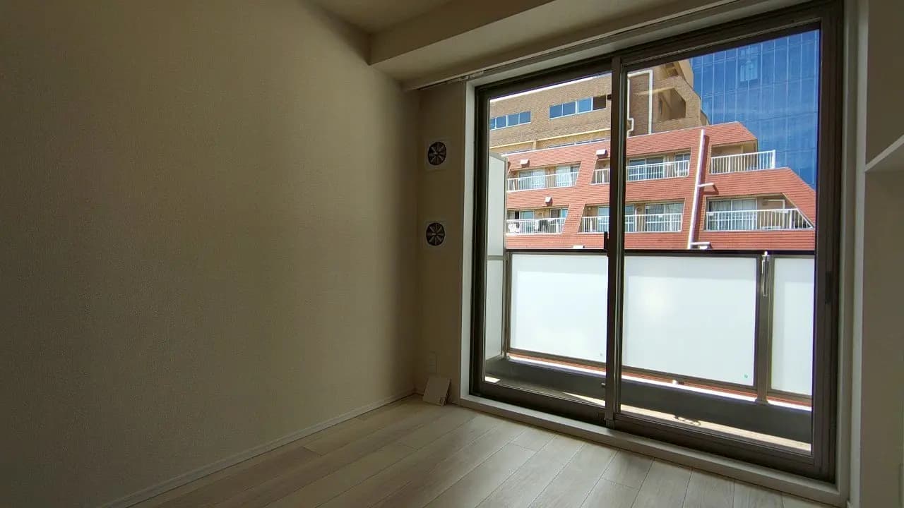 - 明るい光が差し込むシンプルな部屋の内部、窓から外の景色が見える空間、木目調のフローリングと白い壁のインテリア