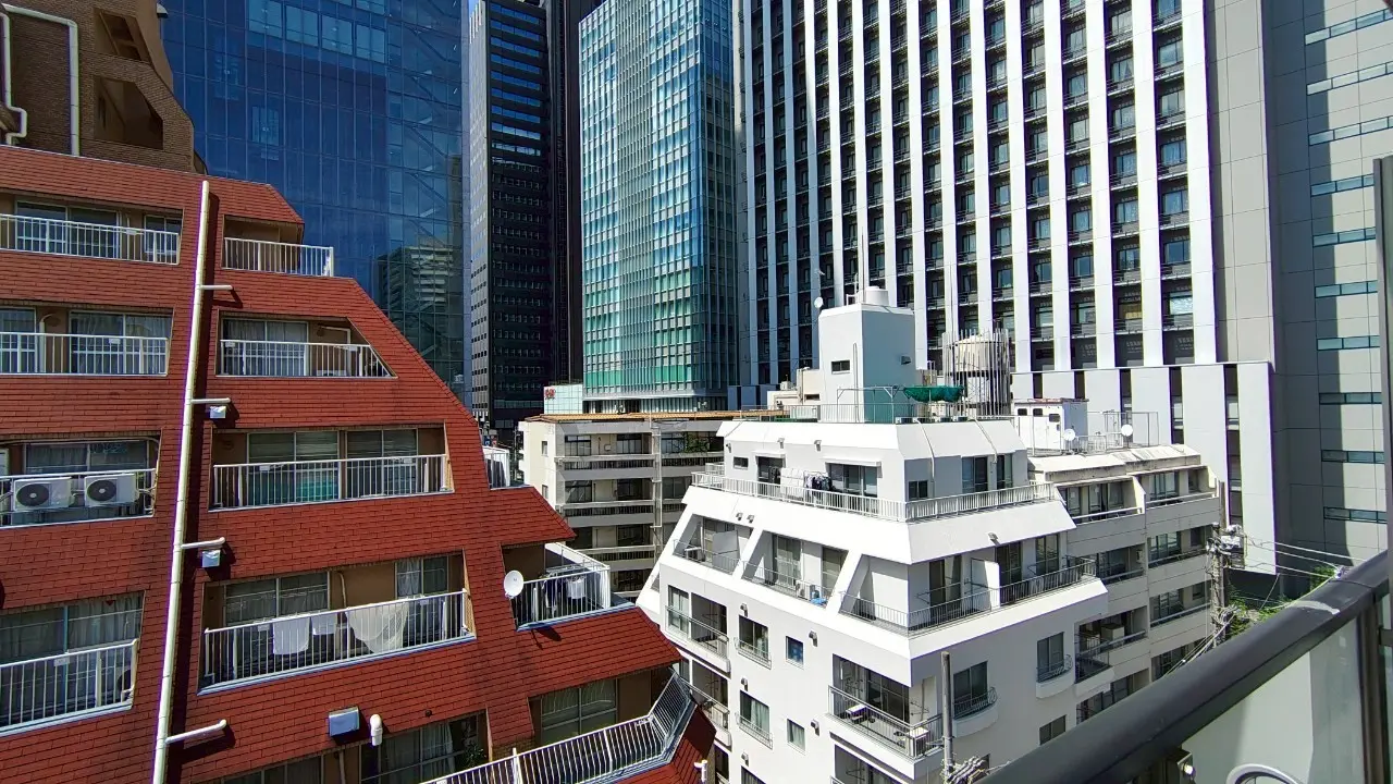 - 都市の高層ビル群と住宅の景観、赤い屋根の建物とガラス張りのビルが並ぶ街並み