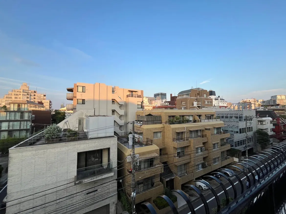 - 都市の風景、複数の建物と青空が広がる、日差しを浴びた住宅街の景観