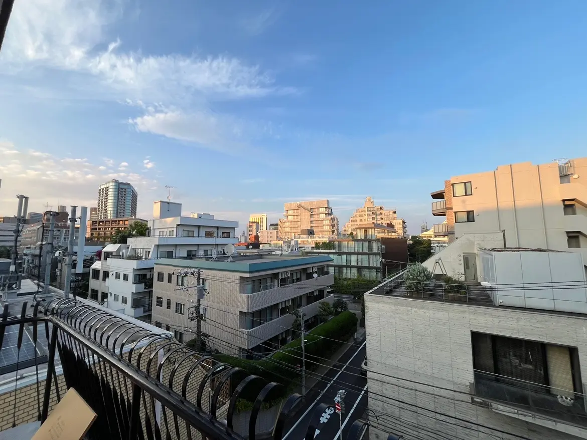 - 都市の風景、低層ビルと高層建築が並ぶ街並み、青空と雲が広がる日中の景色