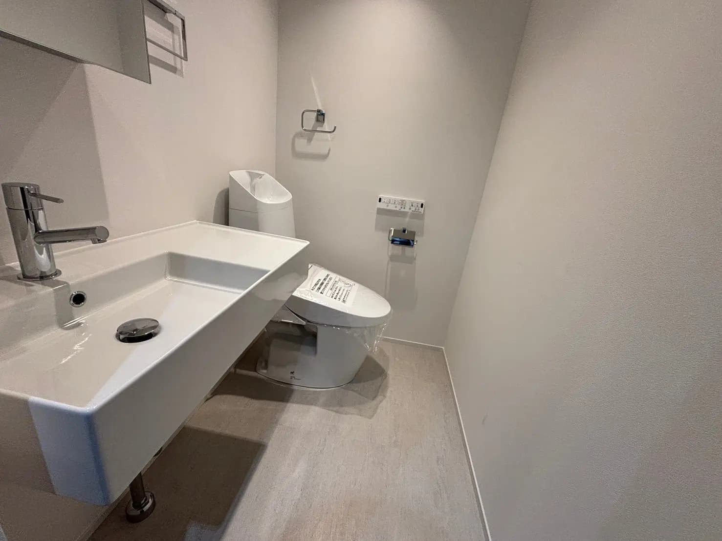 - モダンなデザインのトイレルーム、シンプルな洗面台と白いトイレ、整然とした清潔感のある内装