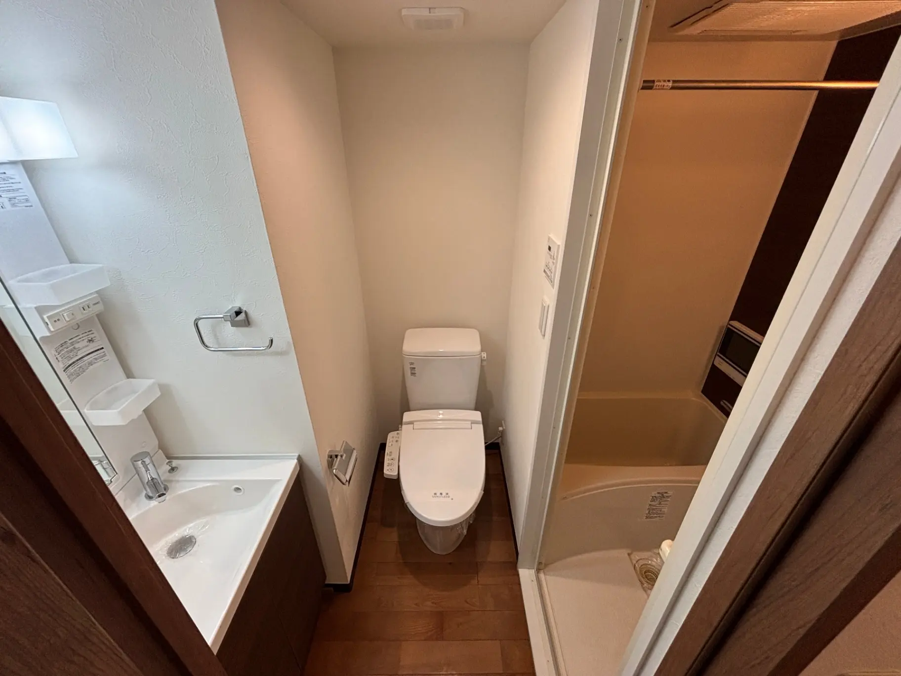 - コンパクトなバスルームの内部、洗面台とトイレが隣接し、バスタブが見える清潔感のあるデザイン