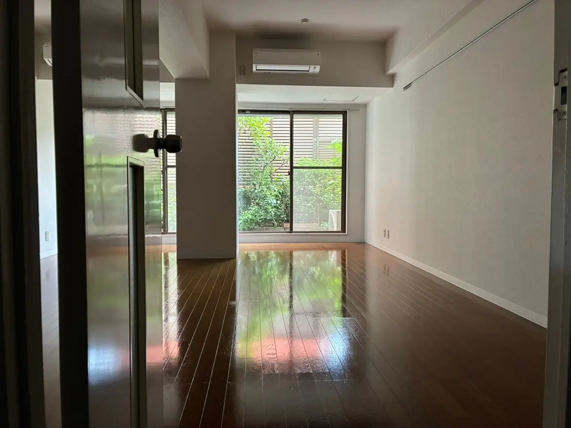 - 明るいリビングルームの入口、広々とした床と大きな窓から見える緑の風景、洗練されたモダンなインテリア