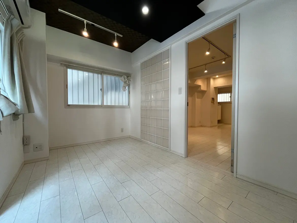 - 明るい色調のフローリングの部屋、窓からの自然光が注ぐ、隣の部屋が見える間仕切りのある室内インテリア