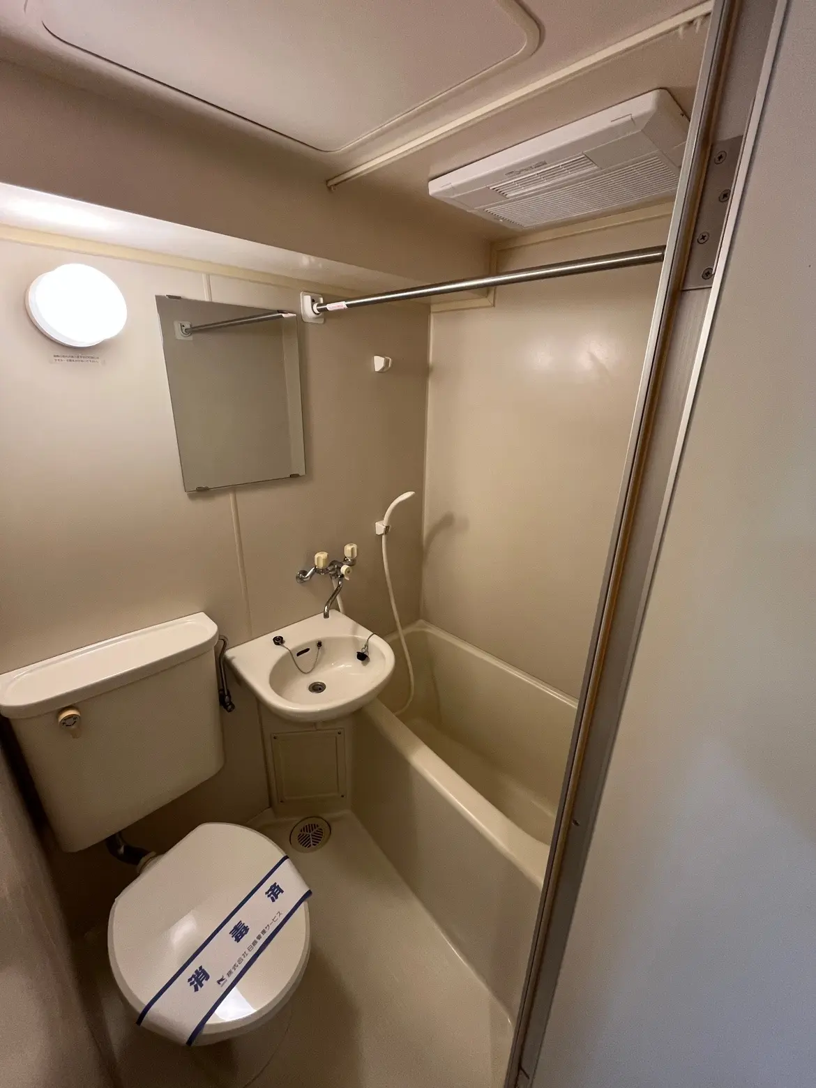 - シンプルなデザインのバスルーム、トイレと洗面台、浴槽とシャワー、壁に光を反射する照明があるインテリア