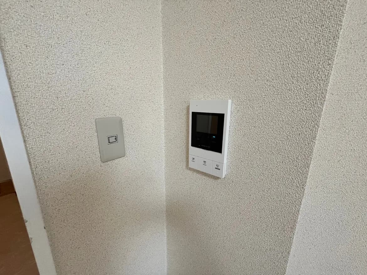 - 壁に取り付けられた温度調節用のデジタルサーモスタットとスイッチ、クリーム色の壁紙のインテリア