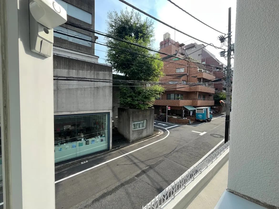 - 都市の風景、近くの建物と交差点が見える窓外の景色、晴れた日と青空が広がる街並み