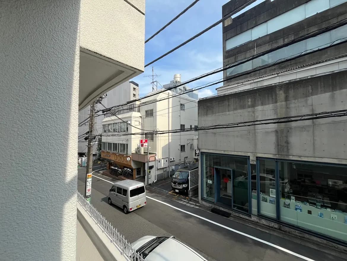 - 都市の街並みを映す窓からの風景、道路を走る車と商業ビルが並ぶ賑やかな通りの景色