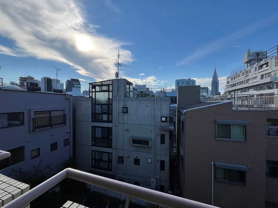- 都市の風景、近くのビル群と遠くに見える高層ビル、青空に浮かぶ雲のある景色