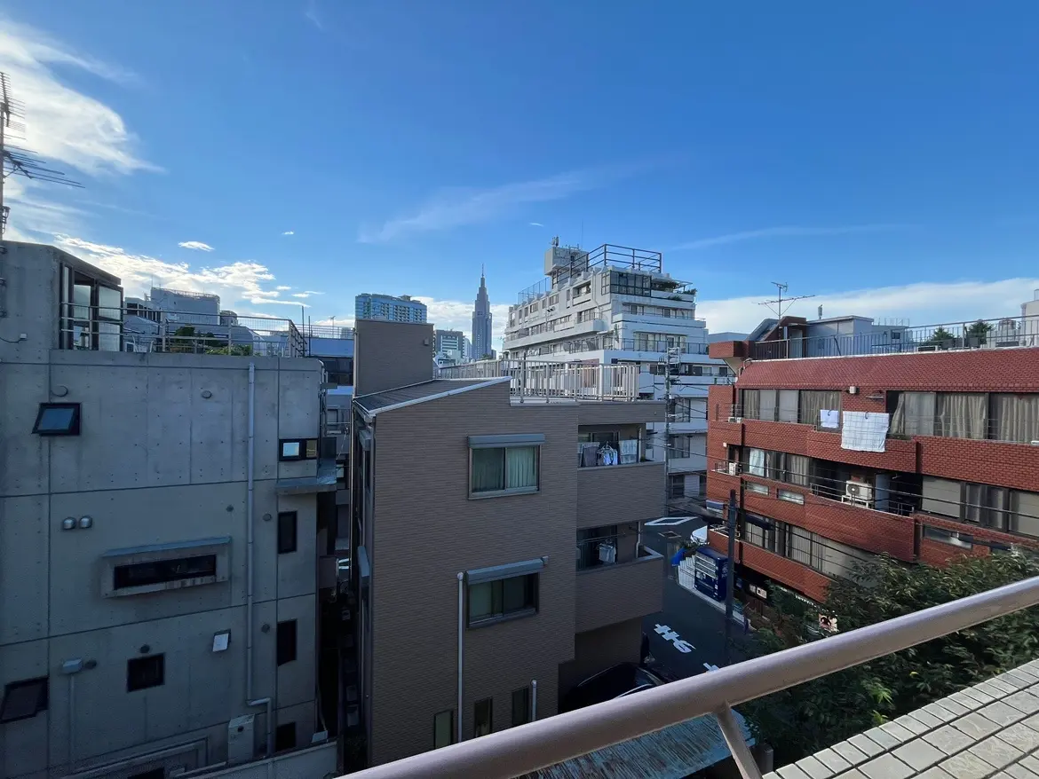 - 都市の風景、近くのビルと遠くの東京タワーが見えるバルコニーからの眺め、青空と雲が広がる背景