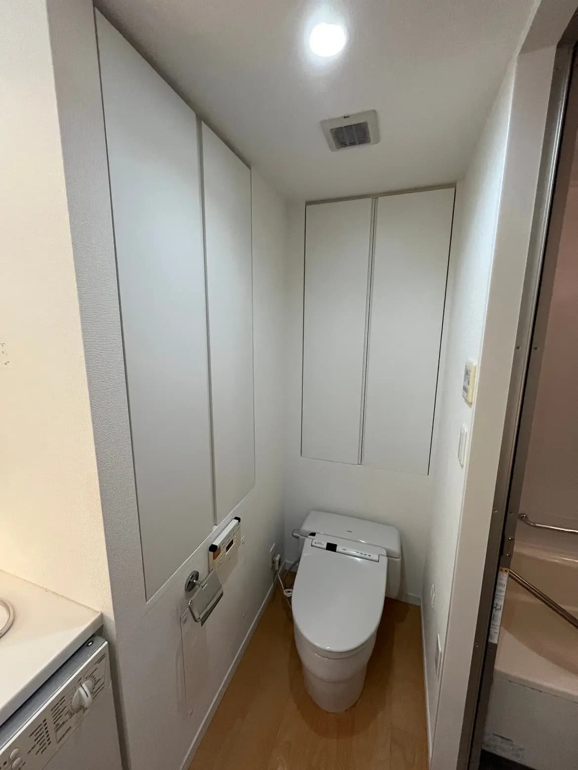 - シンプルで清潔感のあるトイレ、白い壁と木目調の床、最新の洗浄機能付きトイレが配置されたインテリア