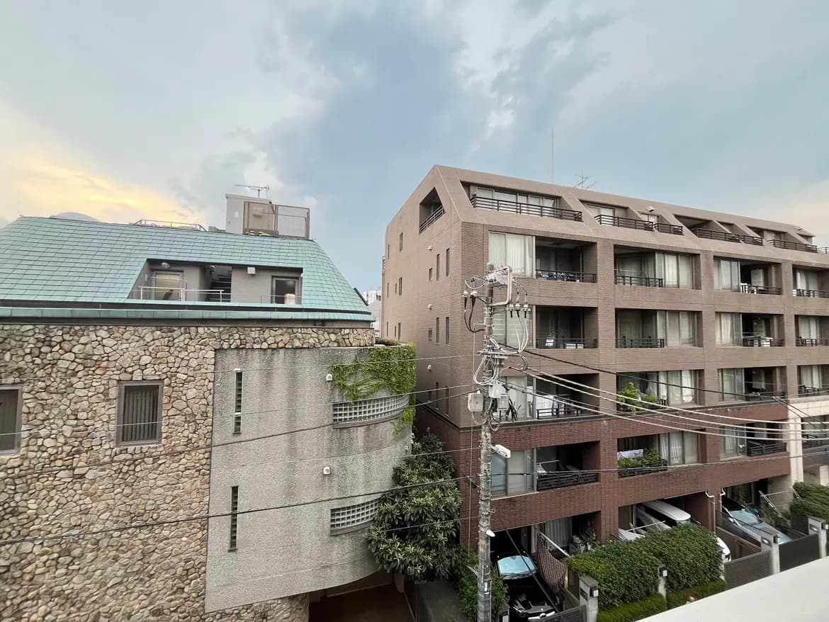 - 石造りとモダンなデザインの建物が並ぶ街並み、曇り空の下に見える住宅地の景観