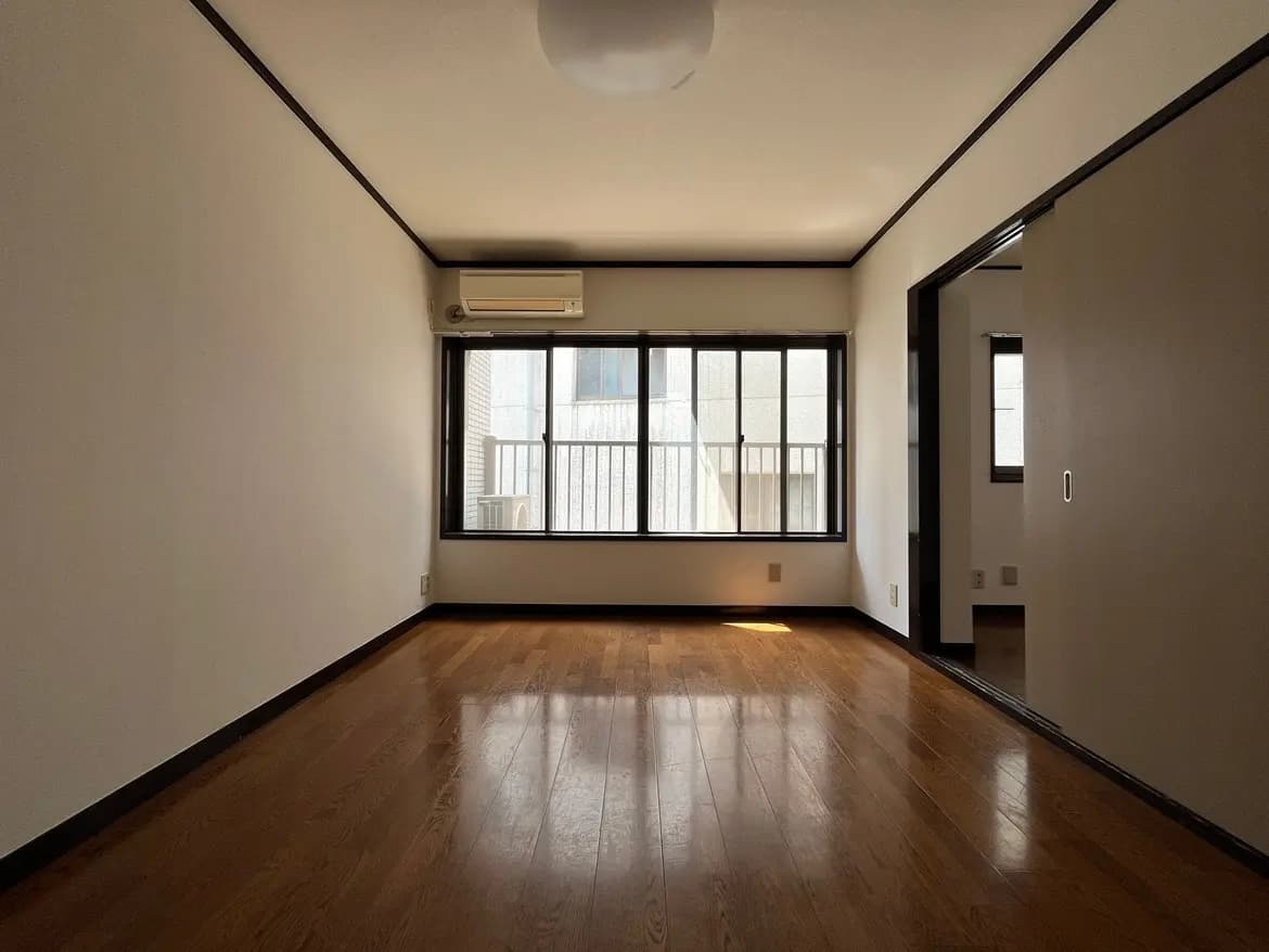 - 明るい窓から自然光が差し込むシンプルなデザインの室内、木製フローリングと壁の取り合いが美しい空間