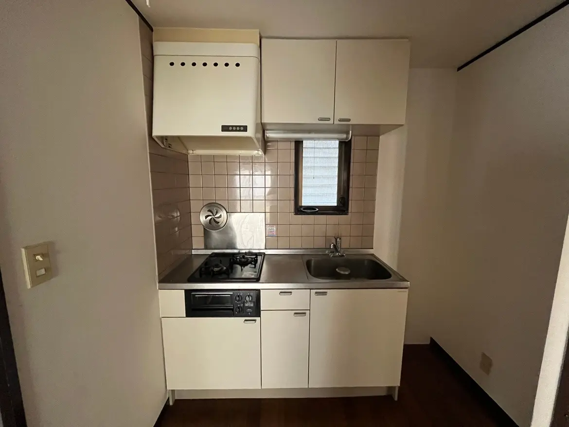 - シンプルで機能的なデザインのキッチン、ステンレス製のシンクとガスコンロ、タイル貼りの壁と明るい窓が特徴のインテリア