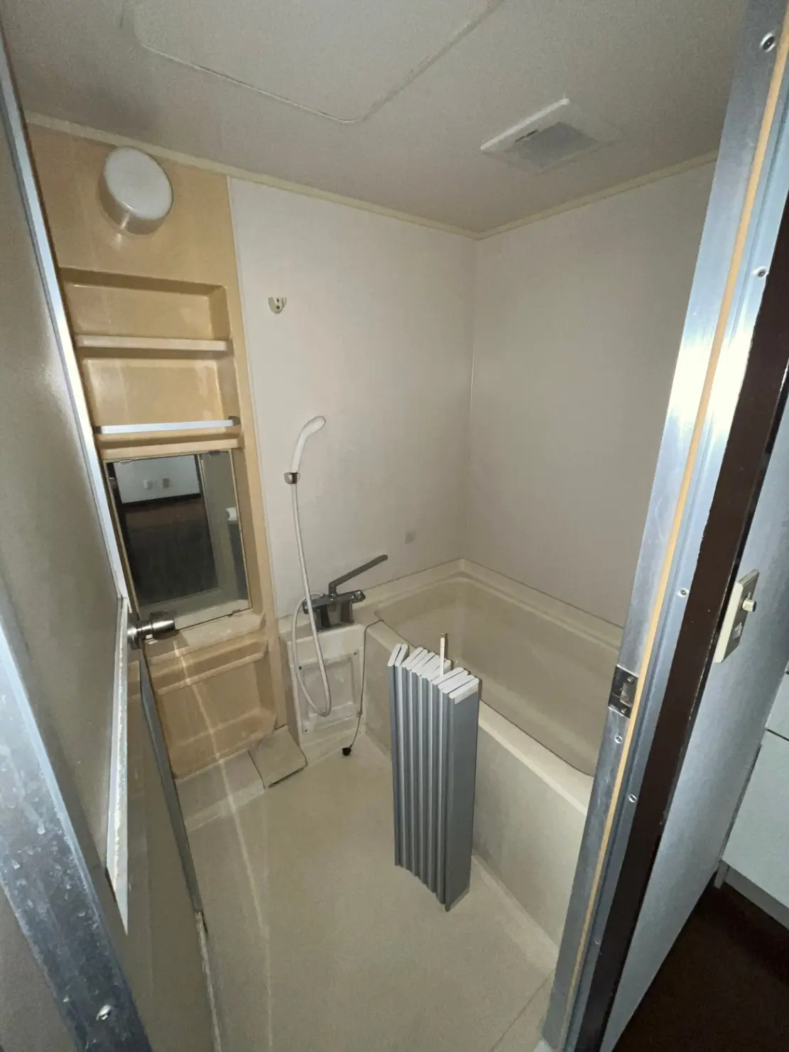 - シンプルなデザインの浴室、白い壁とリラックスできるバスタブ、シャワーと鏡の配置が特徴的なインテリア