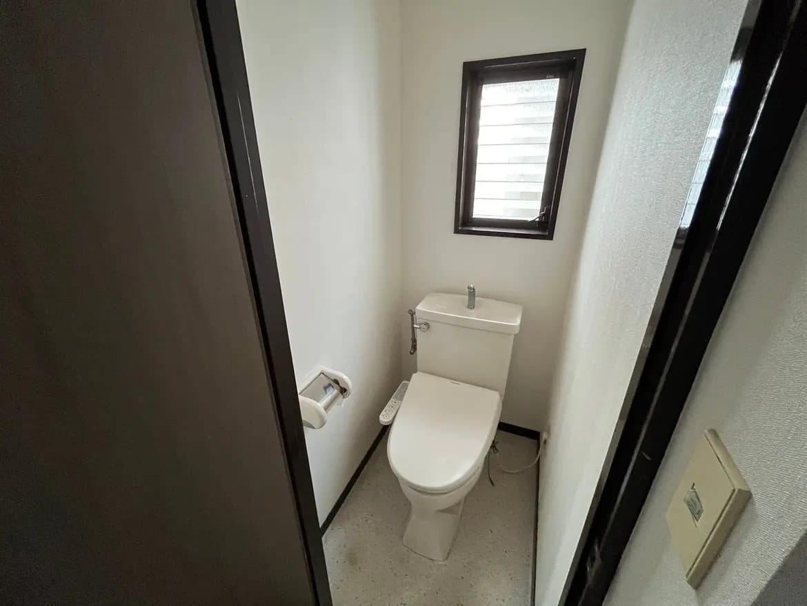 - スタイリッシュなトイレ空間、シンプルなデザインの便器とシャワートイレ、白い壁とコンパクトな窓が印象的なインテリア