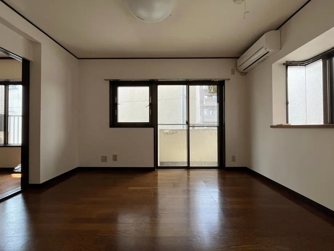 - 明るい色合いの壁が特徴の広々としたリビングルーム、フローリングの床とバルコニーに面した大きな窓があるインテリア