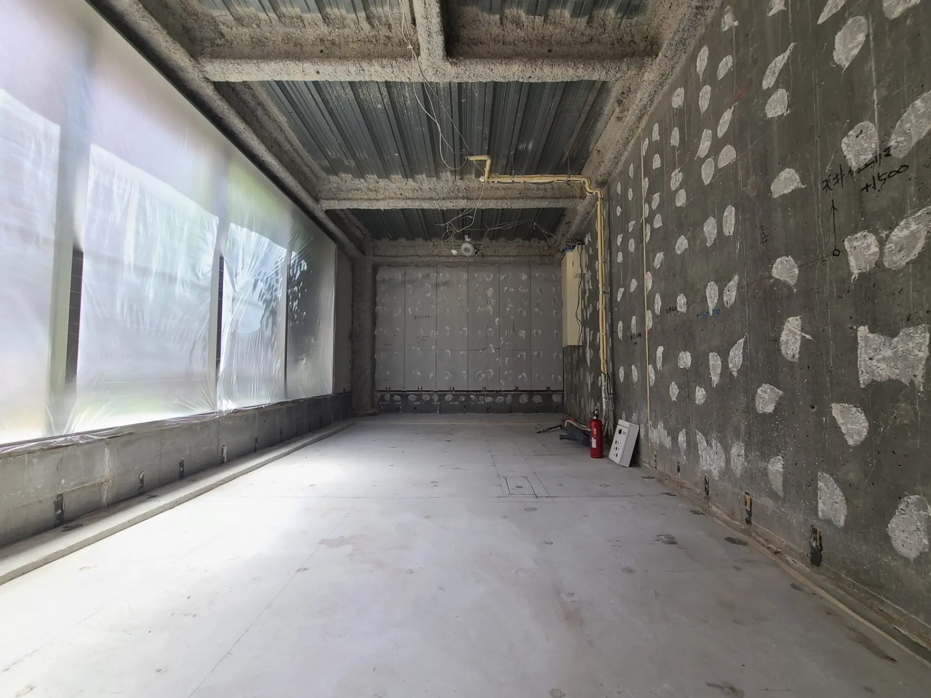 工事中の空のオフィススペース、コンクリートの壁、床に配線の準備がされている建築現場内部
