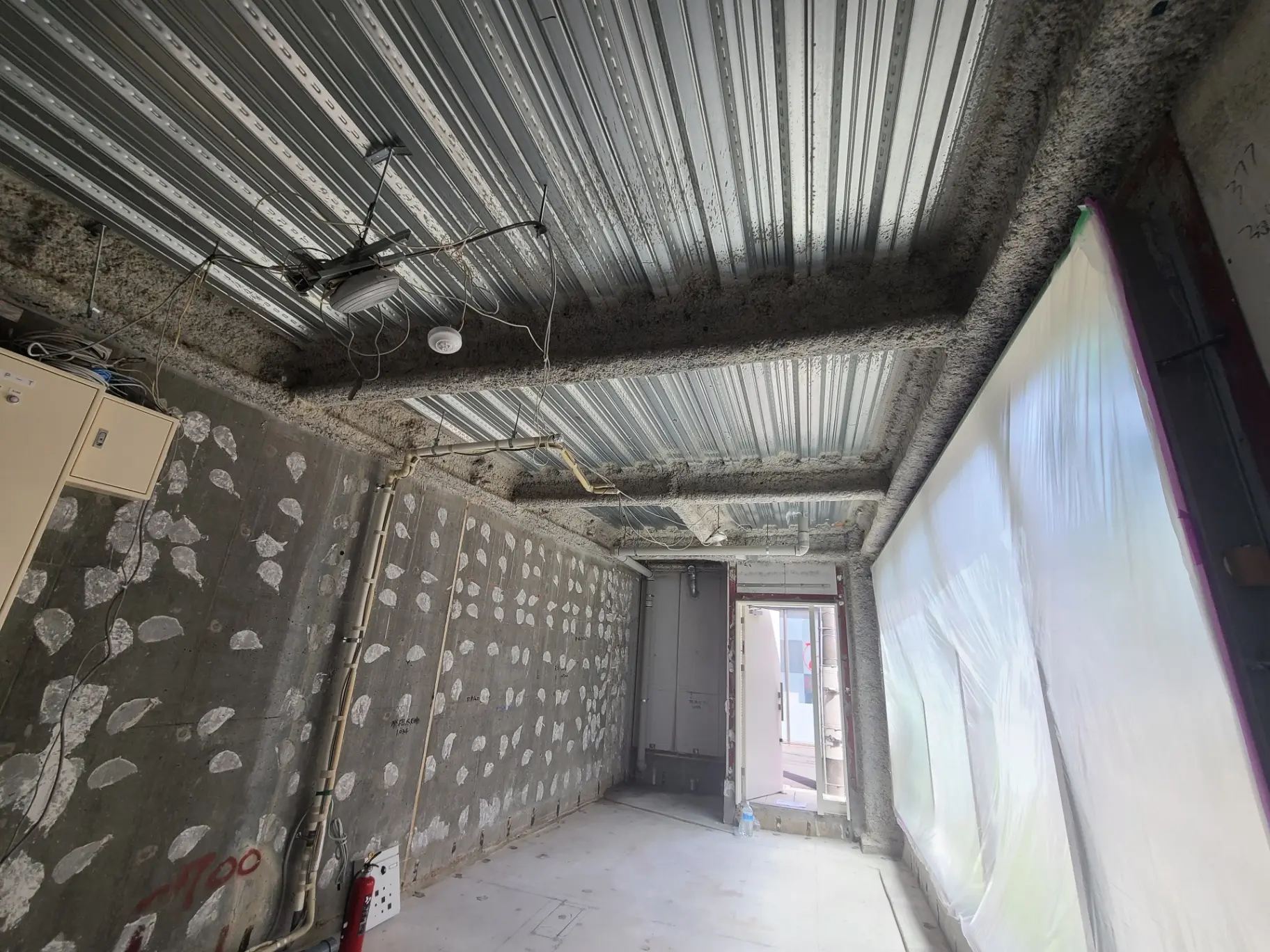 工事中の建物内部、露出した配線とスプリンクラー設備、断熱材が覆われていない壁と天井