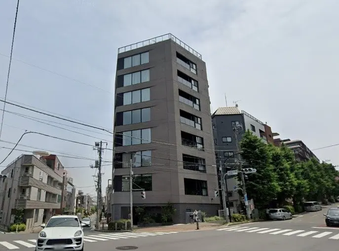 都市の交差点にある現代的なデザインのオフィスビル、日中の通りと車