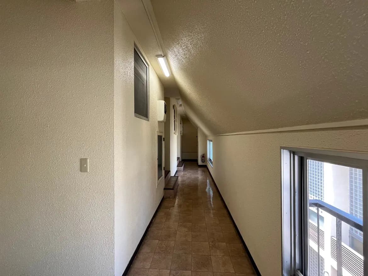 - 明るい廊下、スラント屋根とシンプルなデザインの壁、窓からの光が差し込むシーン