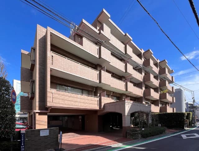 都市の青空の下にあるモダンなレンガ造りのマンション、入り口にアーチ型の通路