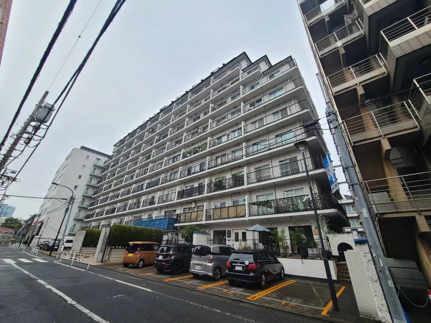 都市部に位置する多層のアパートビル、通り沿いに駐車スペースがある外観