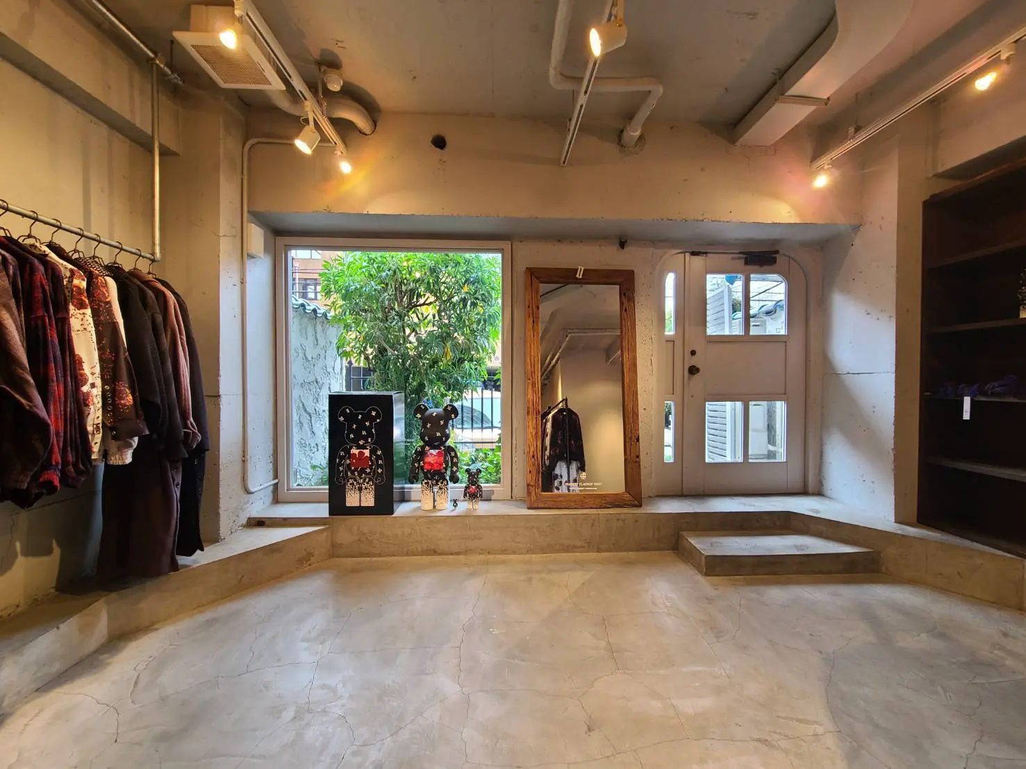 モダンな内装の服飾店舗、洋服が掛けられたラックとアート作品が飾られた店内の様子