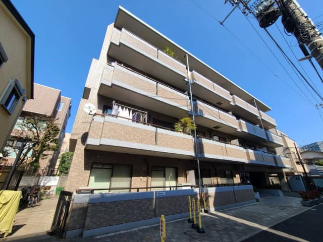 日当たりの良い都市型マンション、明るい青空の下、ベランダに洗濯物が干してある外観