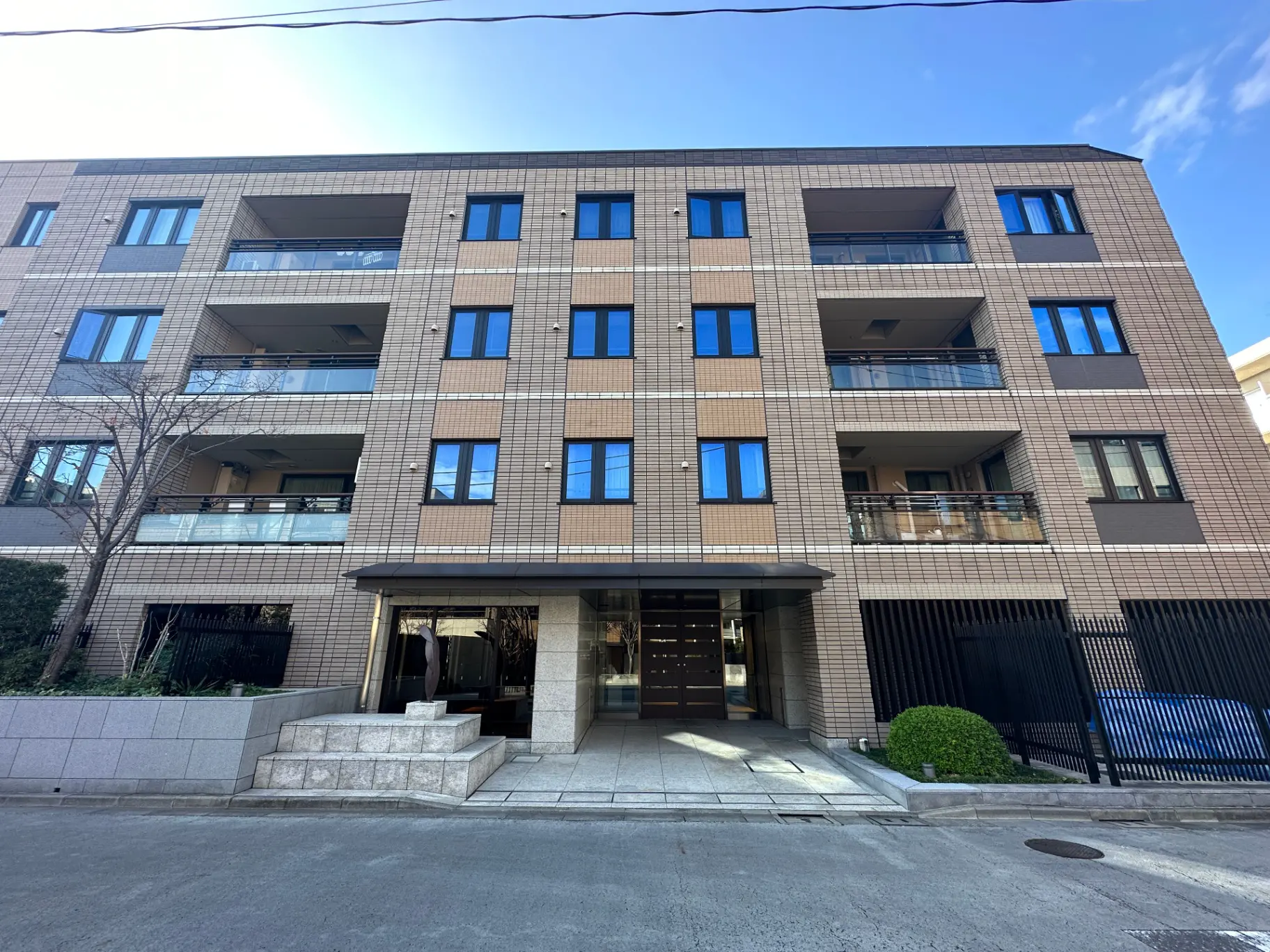 現代的なデザインのマンション外観、複数のバルコニー付き、晴天の下でのクリアな青空