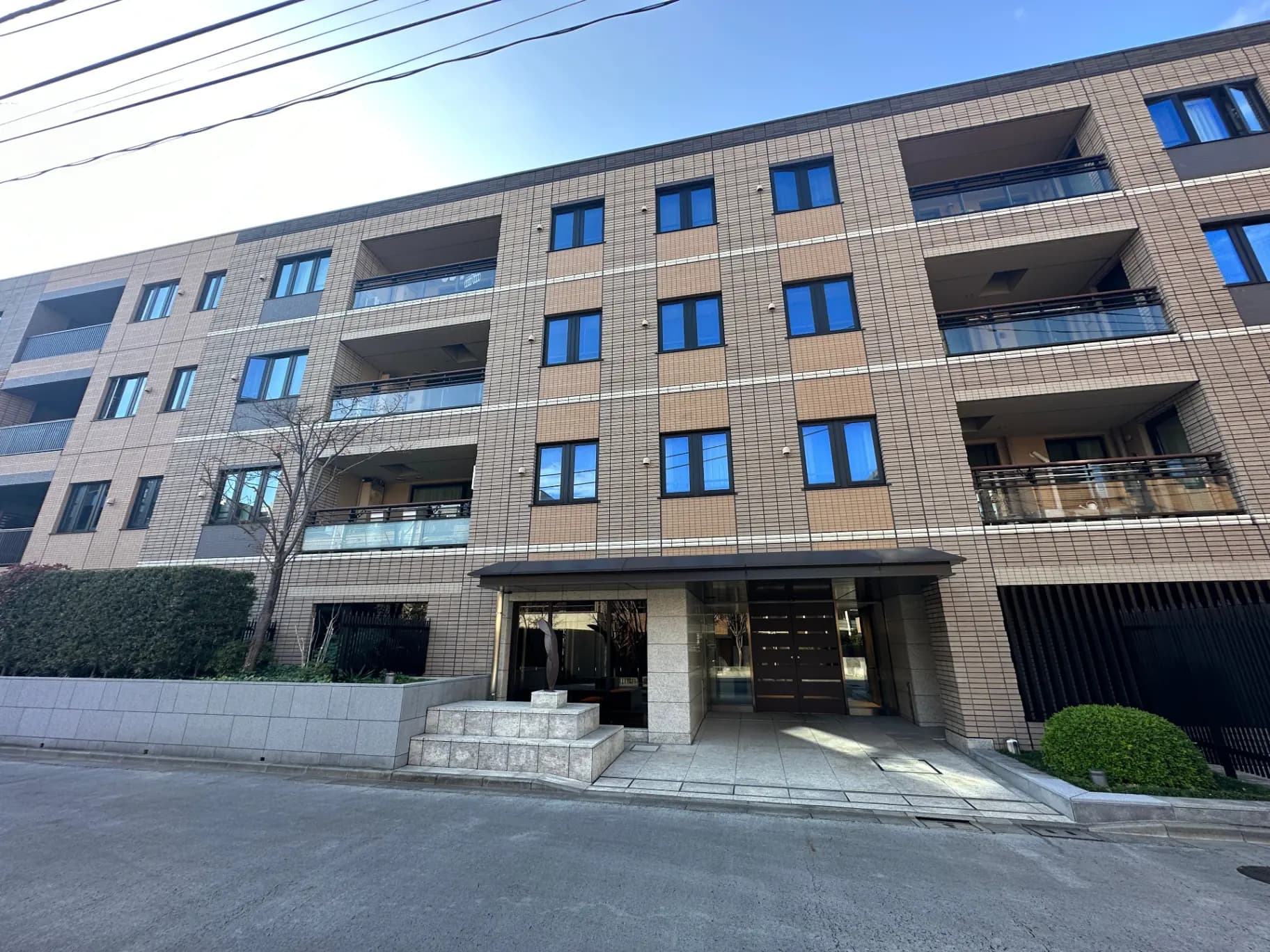 現代的な外観のマンション、明るい日差しと広いエントランス