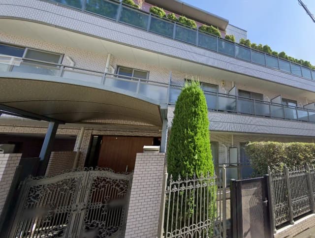 現代的なマンションの外観、白いタイル壁、ガーデニング付きのバルコニー、鉄製の門扉