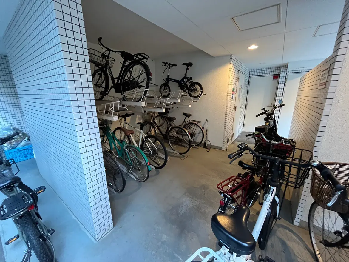 - 自転車の整然とした駐輪場、壁面に取り付けられたラックに置かれた自転車と、床に並ぶ様々なデザインの自転車が見える室内の風景