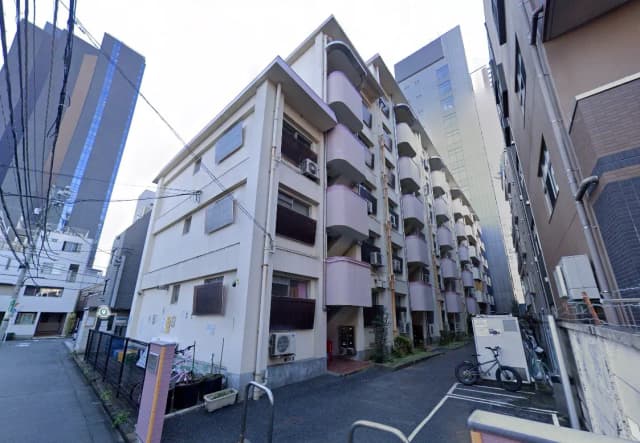 - 都市の中に立つ外観が特徴的なアパートメントビル、隣接する高層ビルと狭い通りの風景