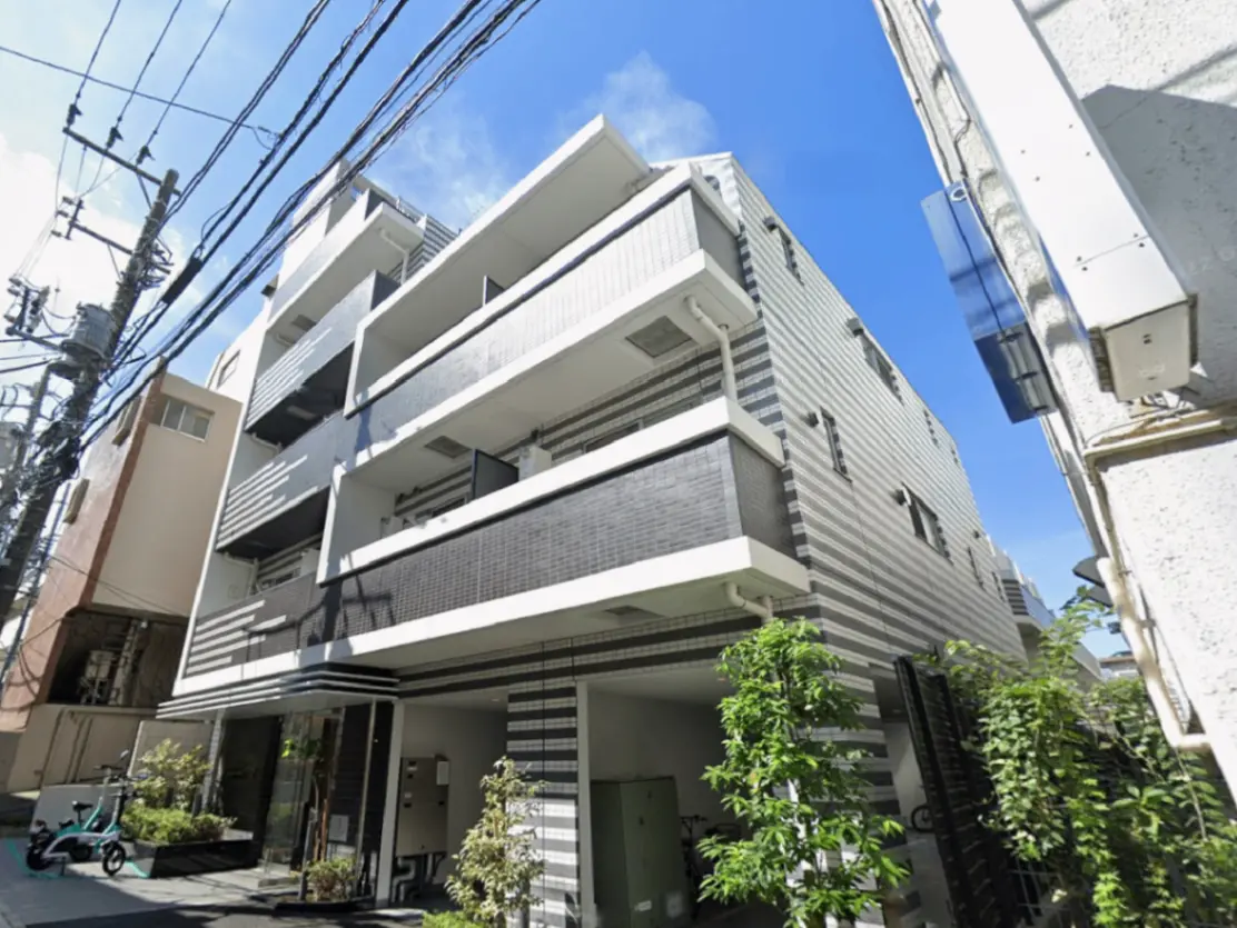 - スタイリッシュな外観の集合住宅、ストライプ模様の外壁、青空の下での撮影、周囲に植えられた緑の植物がある景観