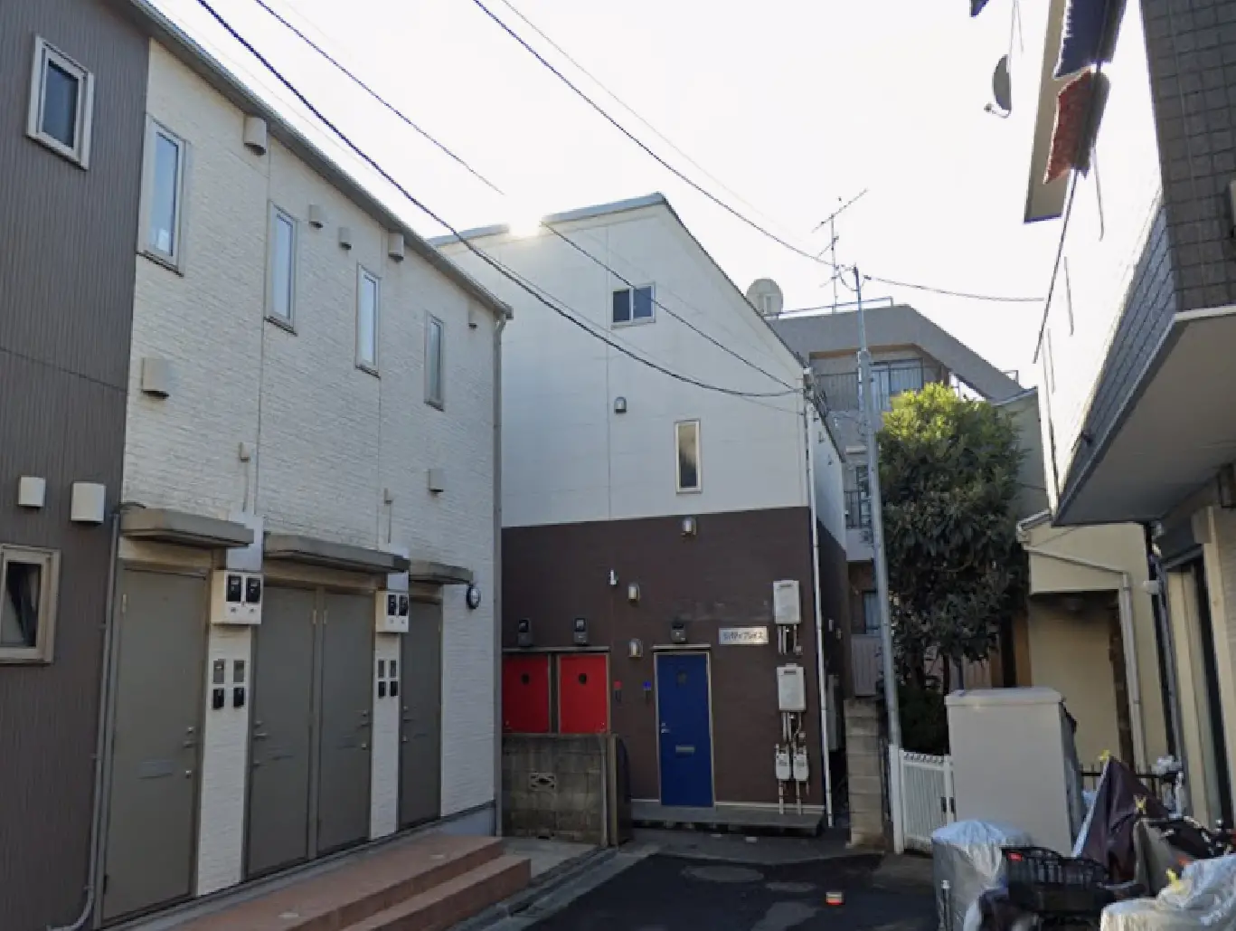 - 住宅街の中にあるモダンなアパートメント、特徴的な外観とカラフルなドアが並ぶエリアの風景