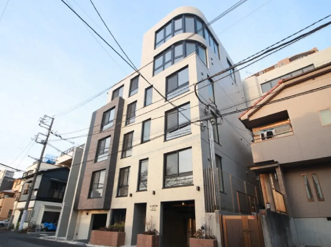 - モダンな外観の集合住宅、広い窓と洗練されたデザインが特徴、周囲には電線と他の住宅が並ぶ景観