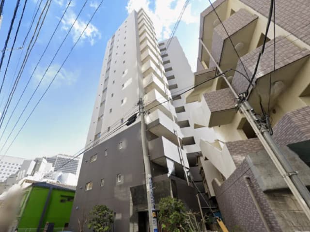 - 高層マンションの外観、隣接する建物と電柱が見える都市の風景、青空を背景にした近代的なデザイン