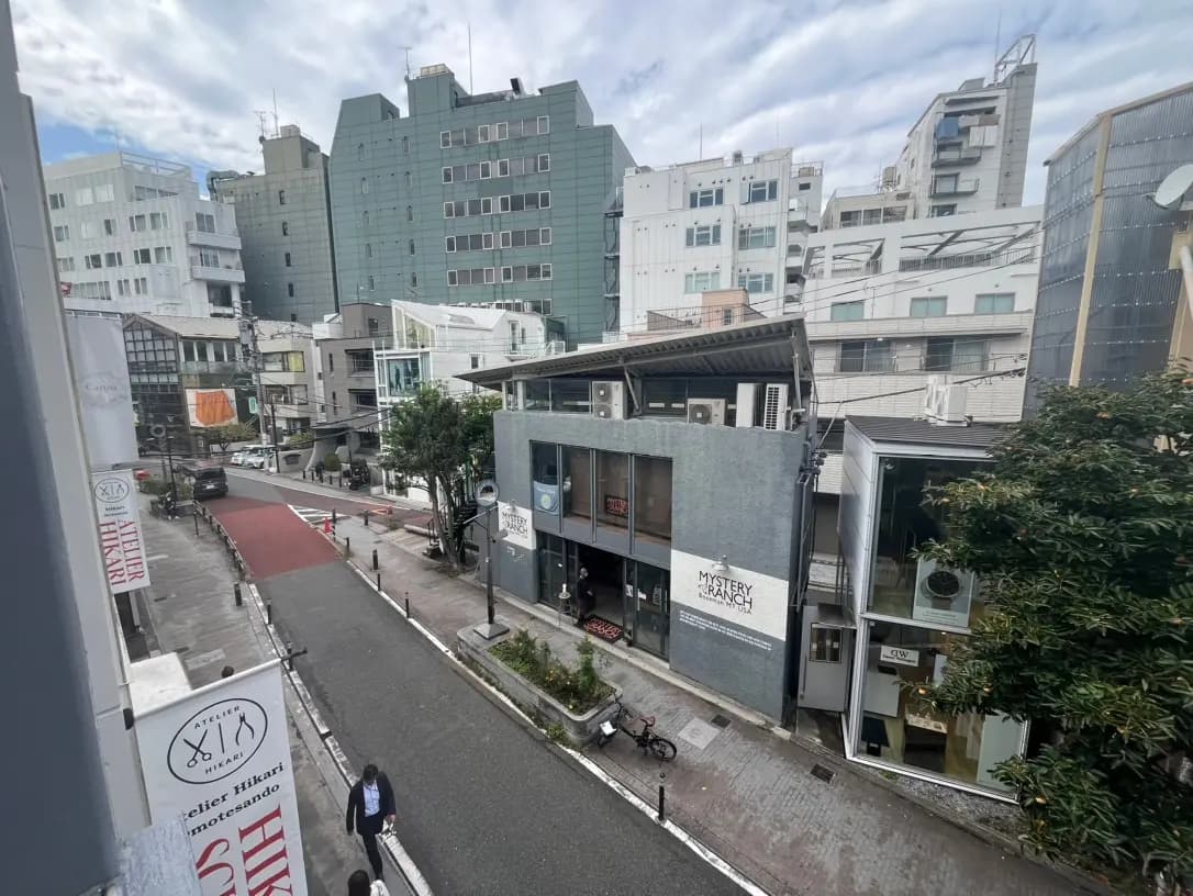 日本の都市部の通りの風景、複数の建物と歩行者、雲がかかる空