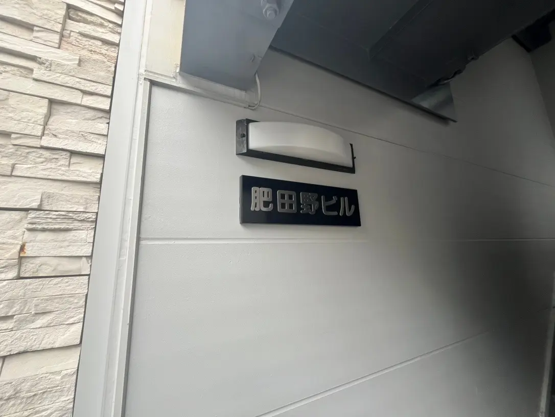 建物の外壁に取り付けられた「駐輪場」の看板、石造り調の壁面に黒背景の標識