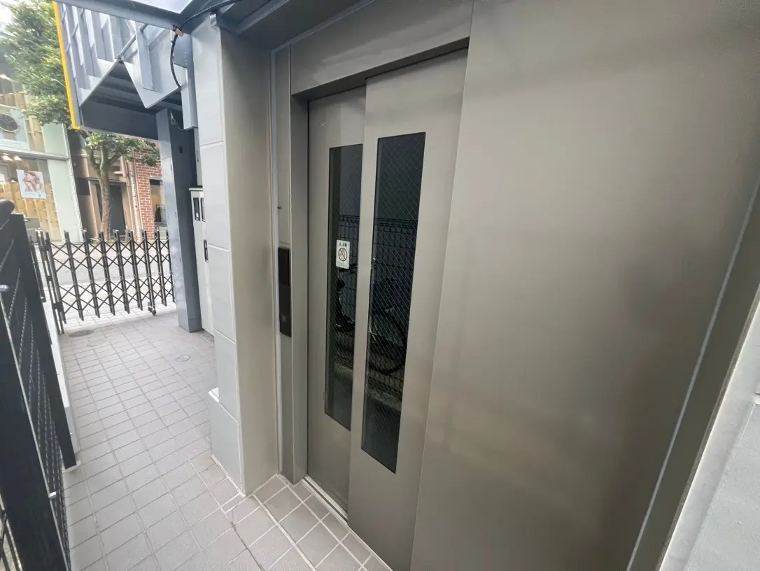 ビルの入口にある現代的なエレベーター、灰色の壁とタイル張りの床、都市の建物の反射