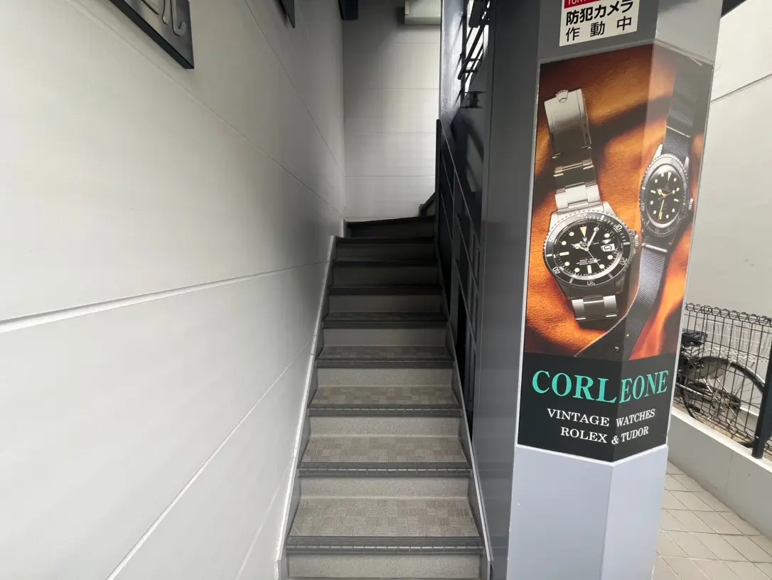 ビルの階段と腕時計の広告看板、ヴィンテージウォッチのロレックスとチュードルのポスター