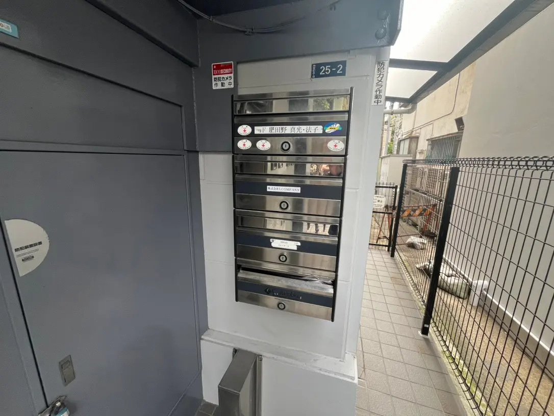 アパートのエントランスにあるインターホンと郵便受け、セキュリティシステムが確認できる屋外コーナー