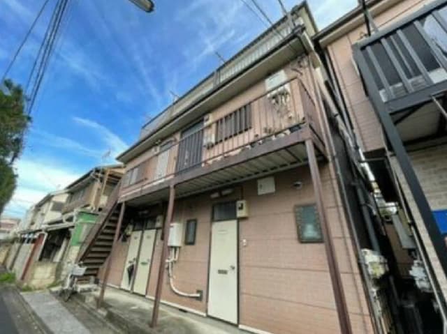- 住宅街に立地する二階建てのアパート、外観はシンプルでバルコニー付き、青空の下での撮影