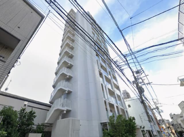 - 白を基調としたモダンなマンション、バルコニーと窓が特徴的で、周囲には電線が張り巡らされた都市の風景