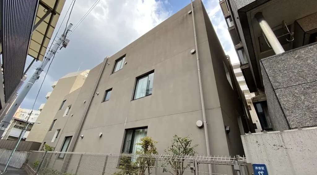 現代的な外観の都市型アパートメント、ベージュの壁と緑の植栽、晴れた日の街中の景観