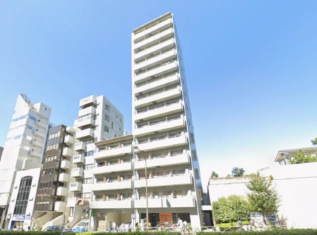 - 現代的なデザインの高層ビル、明るい青空を背景にした外観、周囲に他の建物と緑がある風景