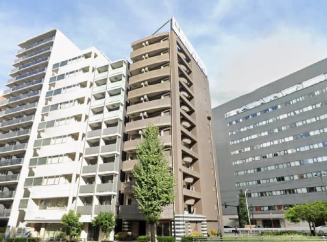 - 都市の中に佇む高層マンション、洗練された外観と緑豊かな庭が調和する景観