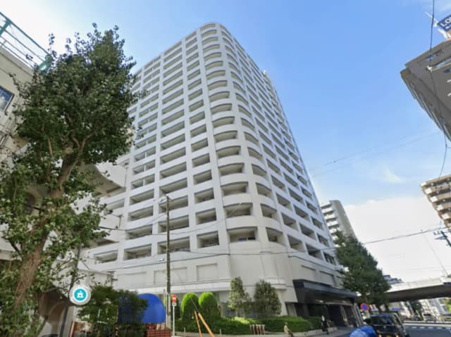 - モダンなデザインの高層マンション、周囲の緑と青空が印象的な外観。