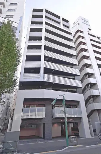 - 現代的なデザインの6階建てマンションの外観、周囲に他の建物が立ち並ぶ都市の風景